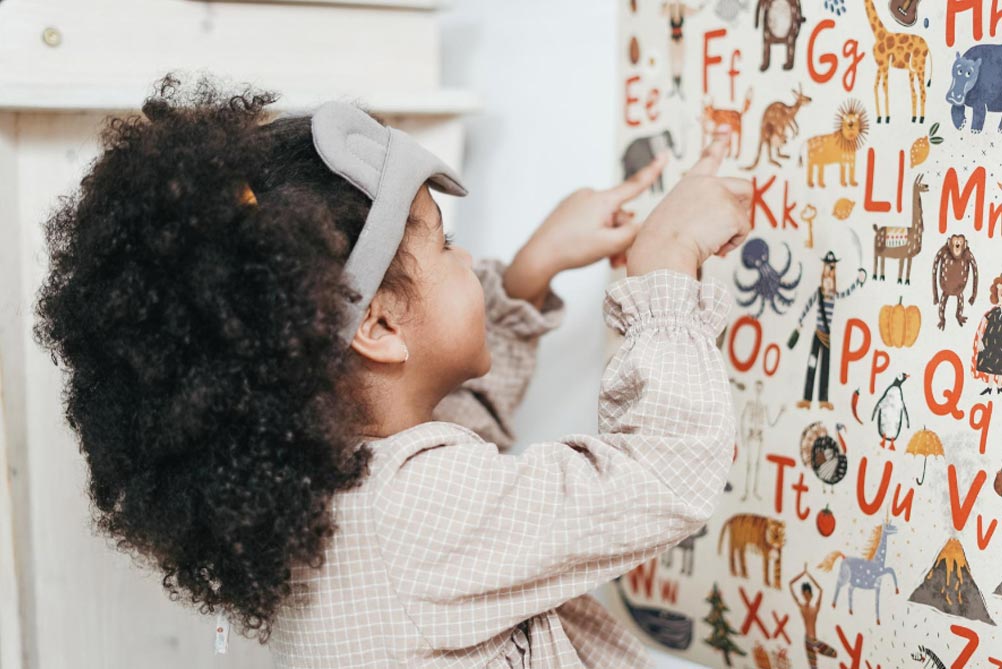 Preschool age girl looking at wall with alphabet letters