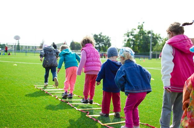 Group of young children practicing physical skills on a playground ladder.
