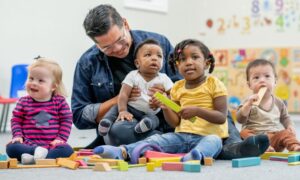 Preschool teacher sits with his diverse group of students in circle time.