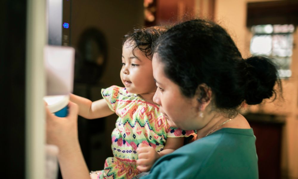 Family Child Care Provider helps a small child get water in a home setting child care.