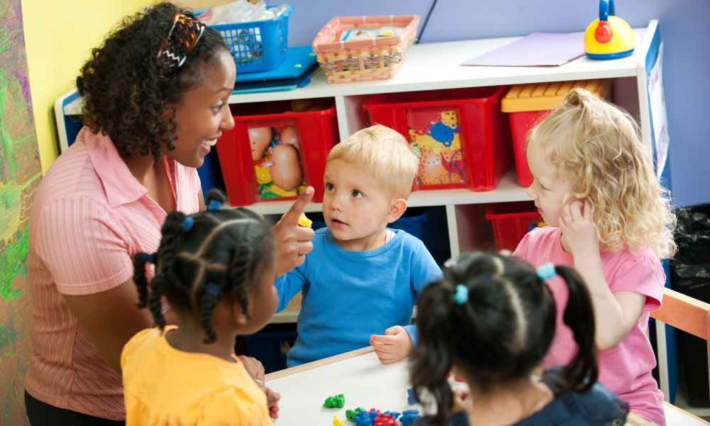 Teacher sits with her diverse preschool students in a circle.