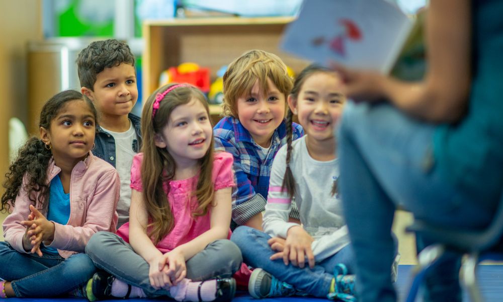 group of children sit for storytime in a preschool setting.