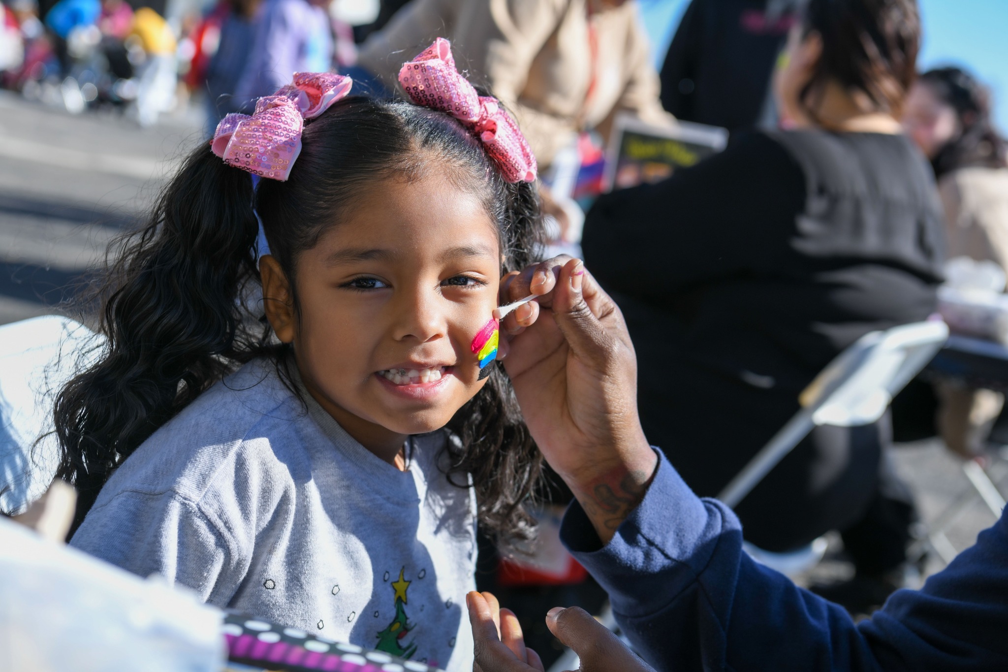 Smiling girl at community fair gets face painted