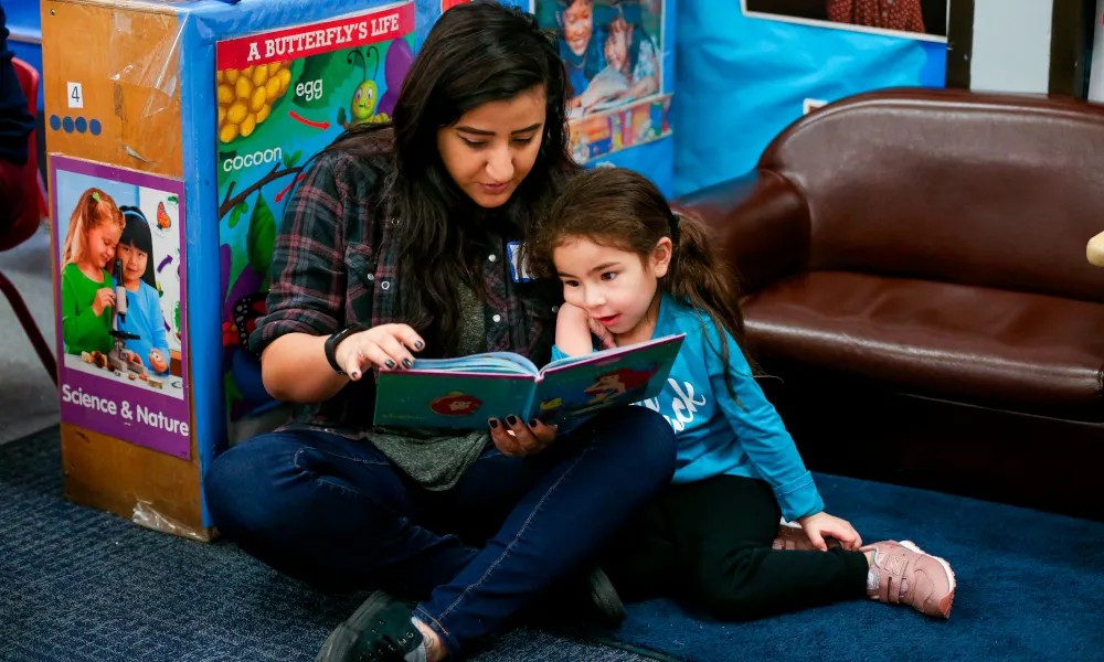 A student teacher and young student read together.