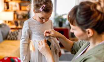 mom and daughter work on an autumn activity - decorating a dress to make a homemade costume.