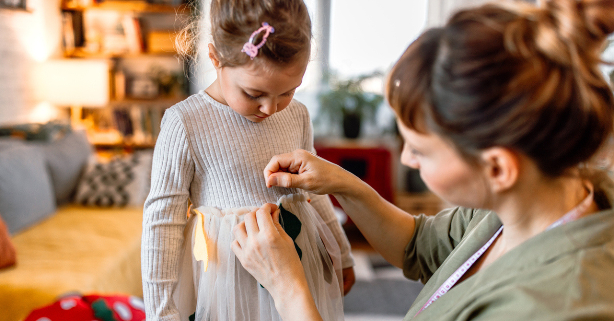 mom and daughter work on an autumn activity - decorating a dress to make a homemade costume.