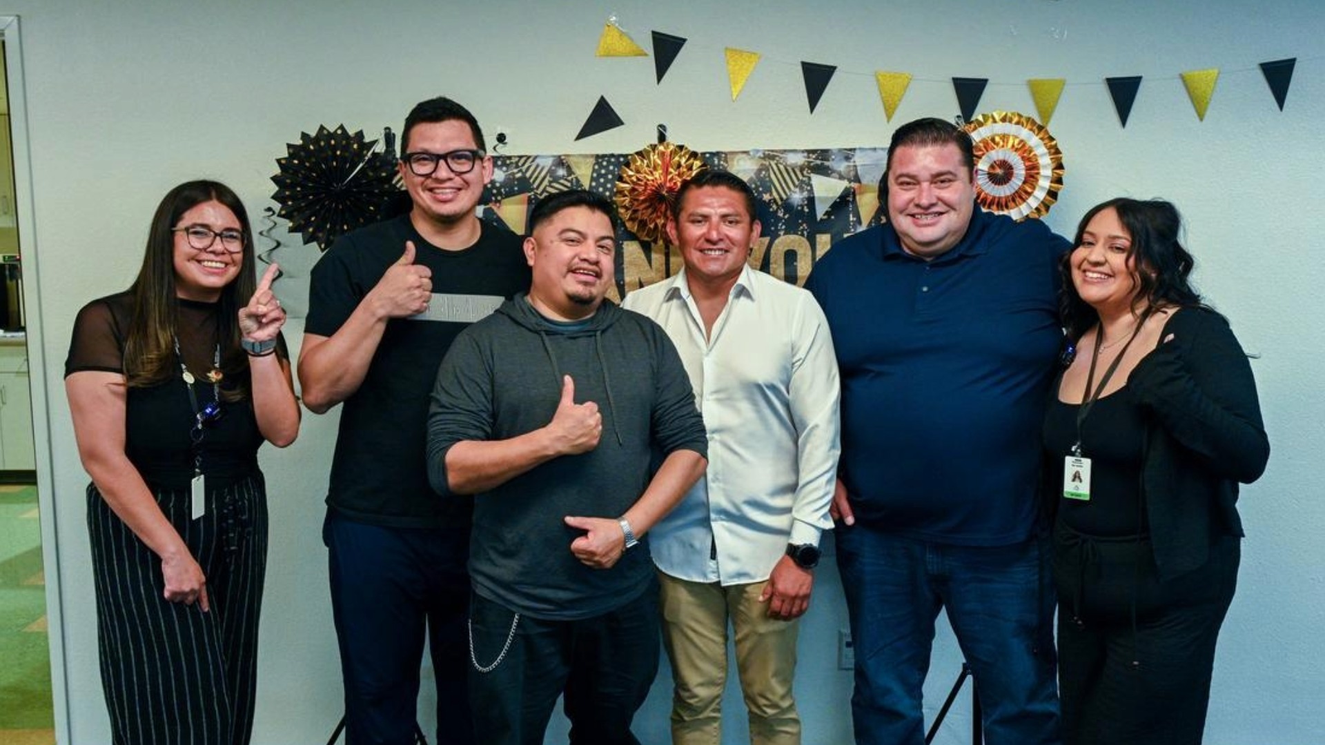 A group of graduates from the Nurturing Fathers Program (CCRC) stand with the course facilitators in front of a congratulatory banner.