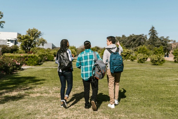 Three ECE college students walking across campus with backpacks